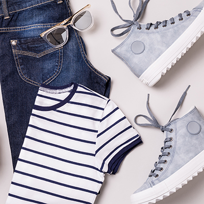 Clothing and accessories - white backpack, jeans, striped t shirt, blue sneakers, sunglasses and belt. Classic casual fashion outfit captured from above (top view, flat lay). Cool young look design.